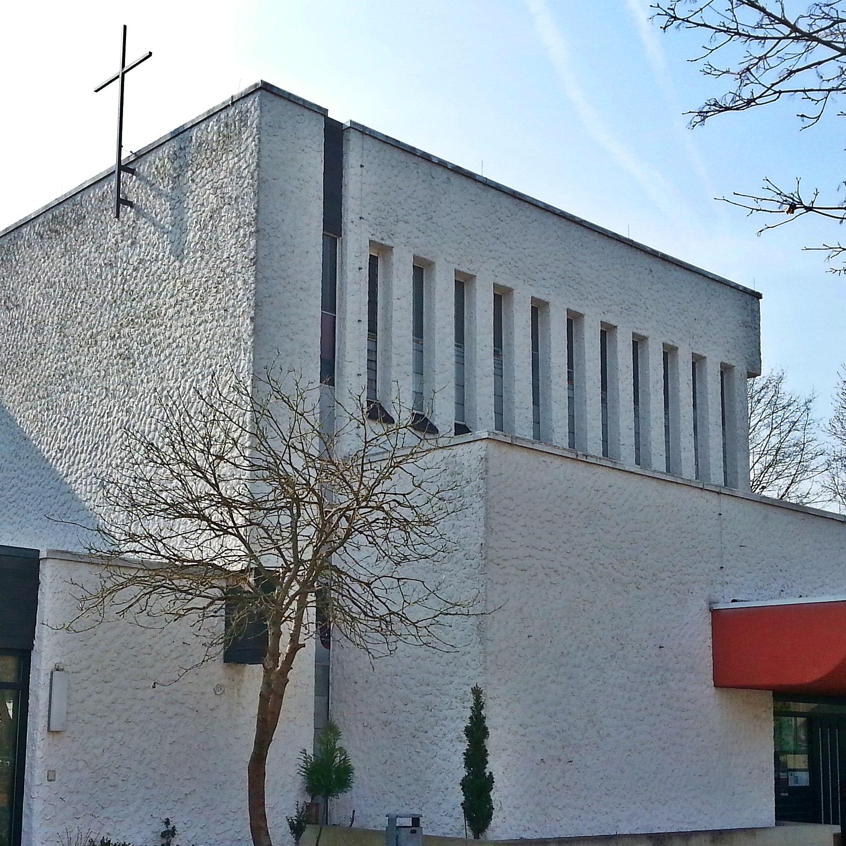 Teilansicht der Kirche St. Hedwig von außen mit Eingang und Kreuz auf dem Dach