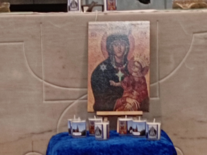 Vor dem Altar in St. Franziskus steht ein Tisch bedeckt mit blauem Tuch darauf ein Bild der Muttergottes und Kerzen. Davor eine Vase mit eine roten Rose und weitere Kerzen