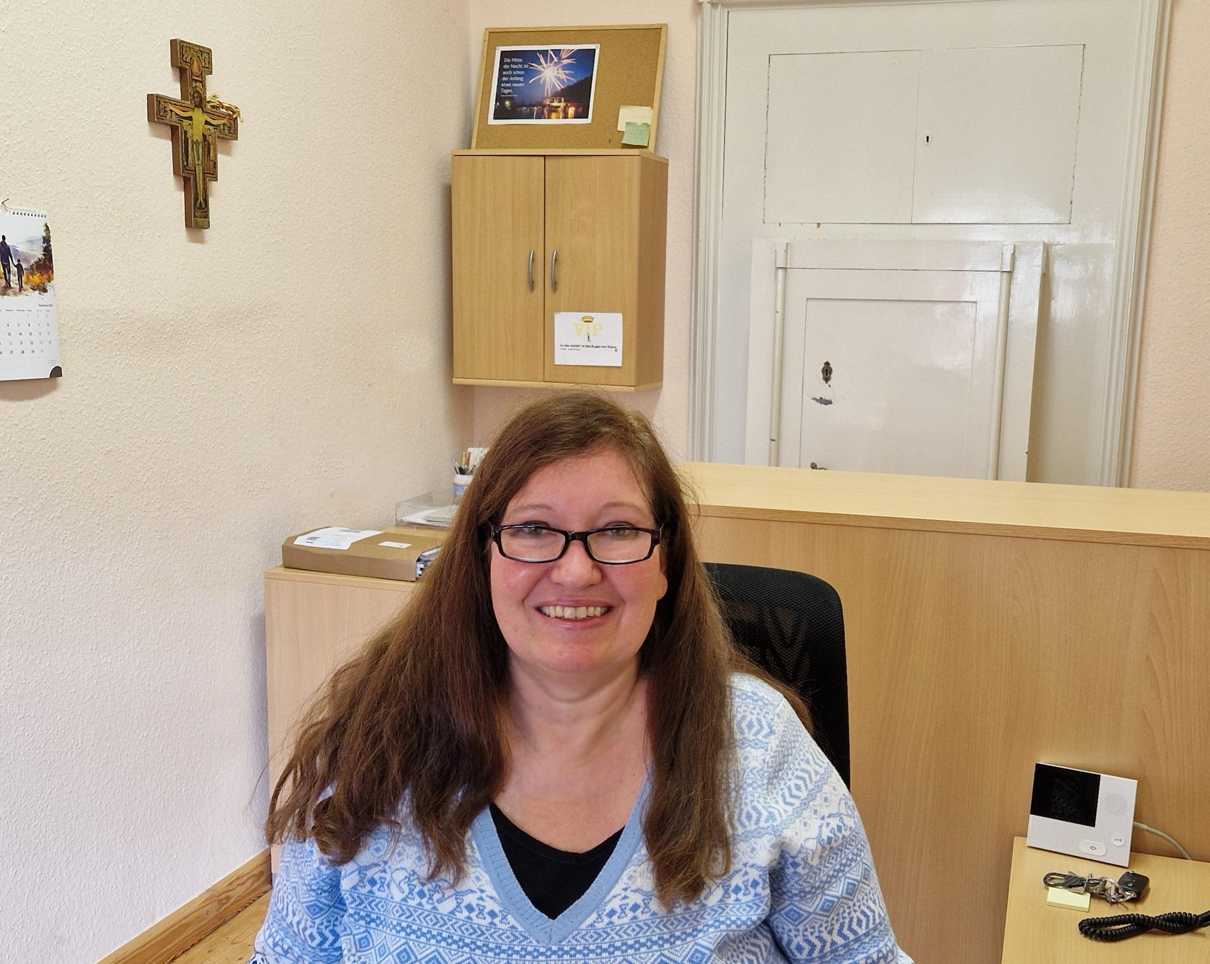 Pfarrsekretärin Andrea Maßfeller im Büro im Hintergrund ein Kreuz