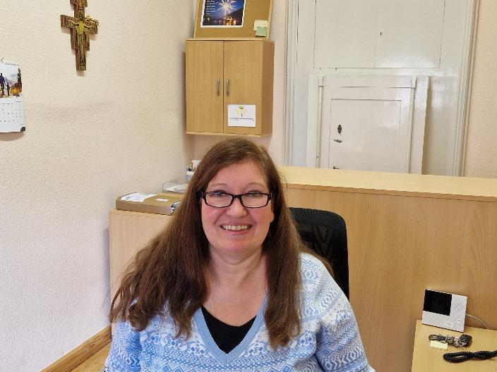 Pfarrsekretärin Andrea Maßfeller im Büro im Hintergrund ein Kreuz