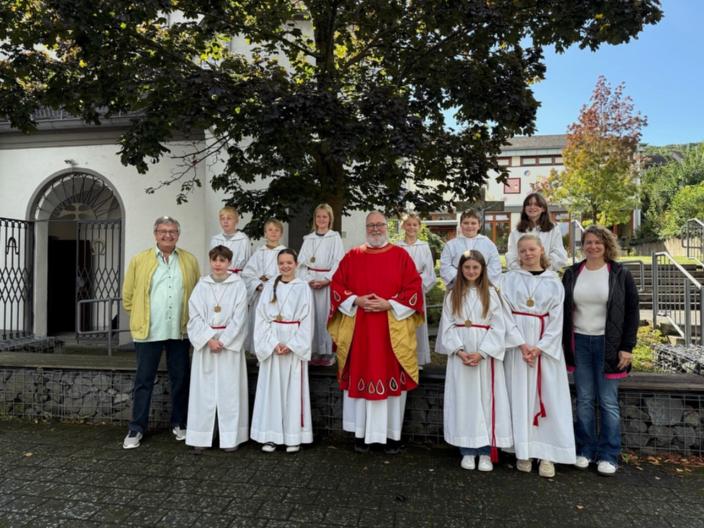 Pfarrer Michael Frevel in rotem lithurgischen Gewand der Mitte von einer Gruppe junger Ministranten