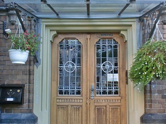 Man sieht die Tür des Pfarrhauses sowie drumherum Backsteine des Gebäudes sowie besondere Fenster über der Tür (c) Andrea Maßfeller Man sieht die Tür des Pfarrhauses sowie drumherum Backsteine des Gebäudes sowie besondere Fenster über der Tür