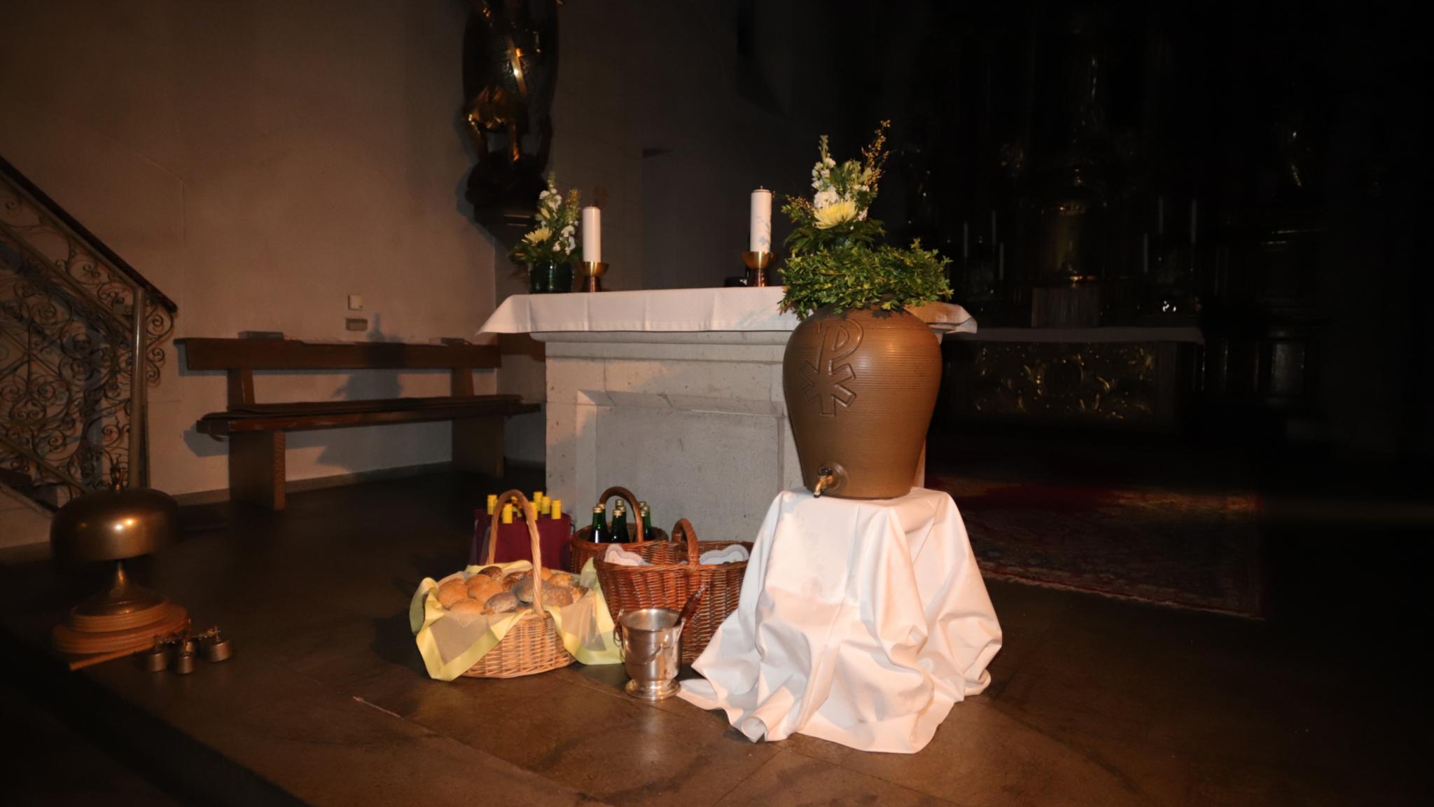 Vor dem Altar der St. Laurentiuskirche in Koblenz stehen Körbe gefüllt mit Osterbrötchen, Traubensaft- und Weinflaschen, Weihwasserkessel und Weihwasserbehälter (c) Jakob Rosenbaum für die Pfarrei Koblenz St. Aposteln Vor dem Altar der St. Laurentiuskirche in Koblenz stehen Körbe gefüllt mit Osterbrötchen, Traubensaft- und Weinflaschen, Weihwasserkessel und Weihwasserbehälter