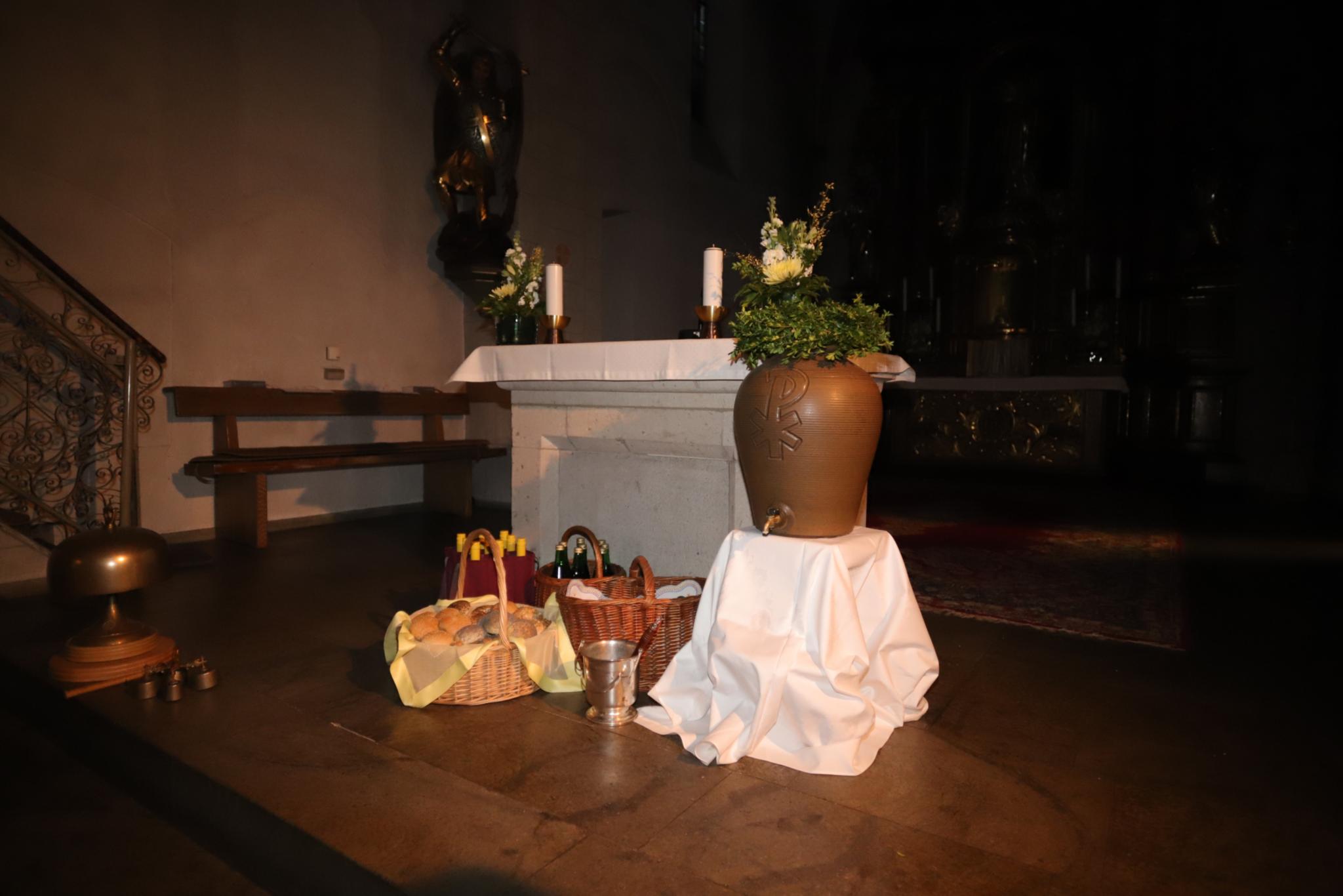 Vor dem Altar der St. Laurentiuskirche in Koblenz stehen Körbe gefüllt mit Osterbrötchen, Traubensaft- und Weinflaschen, Weihwasserkessel und Weihwasserbehälter (c) Jakob Rosenbaum für die Pfarrei Koblenz St. Aposteln Vor dem Altar der St. Laurentiuskirche in Koblenz stehen Körbe gefüllt mit Osterbrötchen, Traubensaft- und Weinflaschen, Weihwasserkessel und Weihwasserbehälter