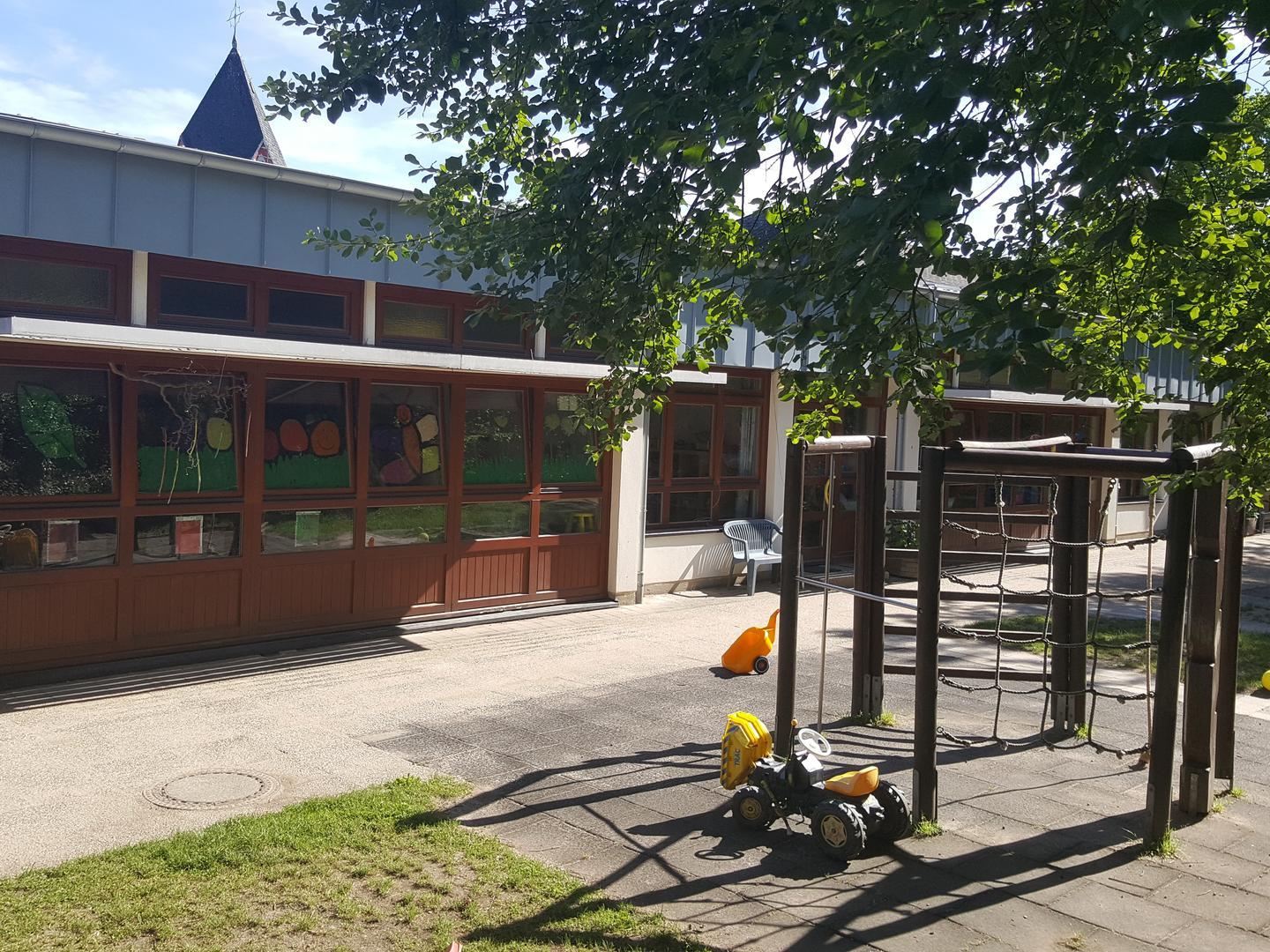 Blick von Außengelände mit Klettergerüst auf das Gebäude der KiTa