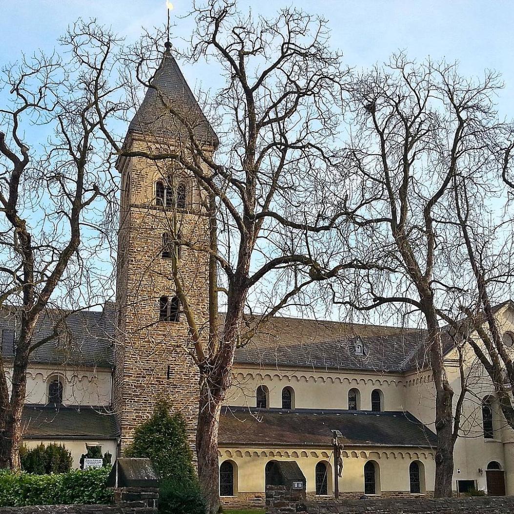 Kirche St. Laurentius Koblenz (c) Andrea Maßfeller Kirche St. Laurentius von außen, von der Straßenseite her, die großen Kastanien davor haben keine Blätter. Blauer Himmel.