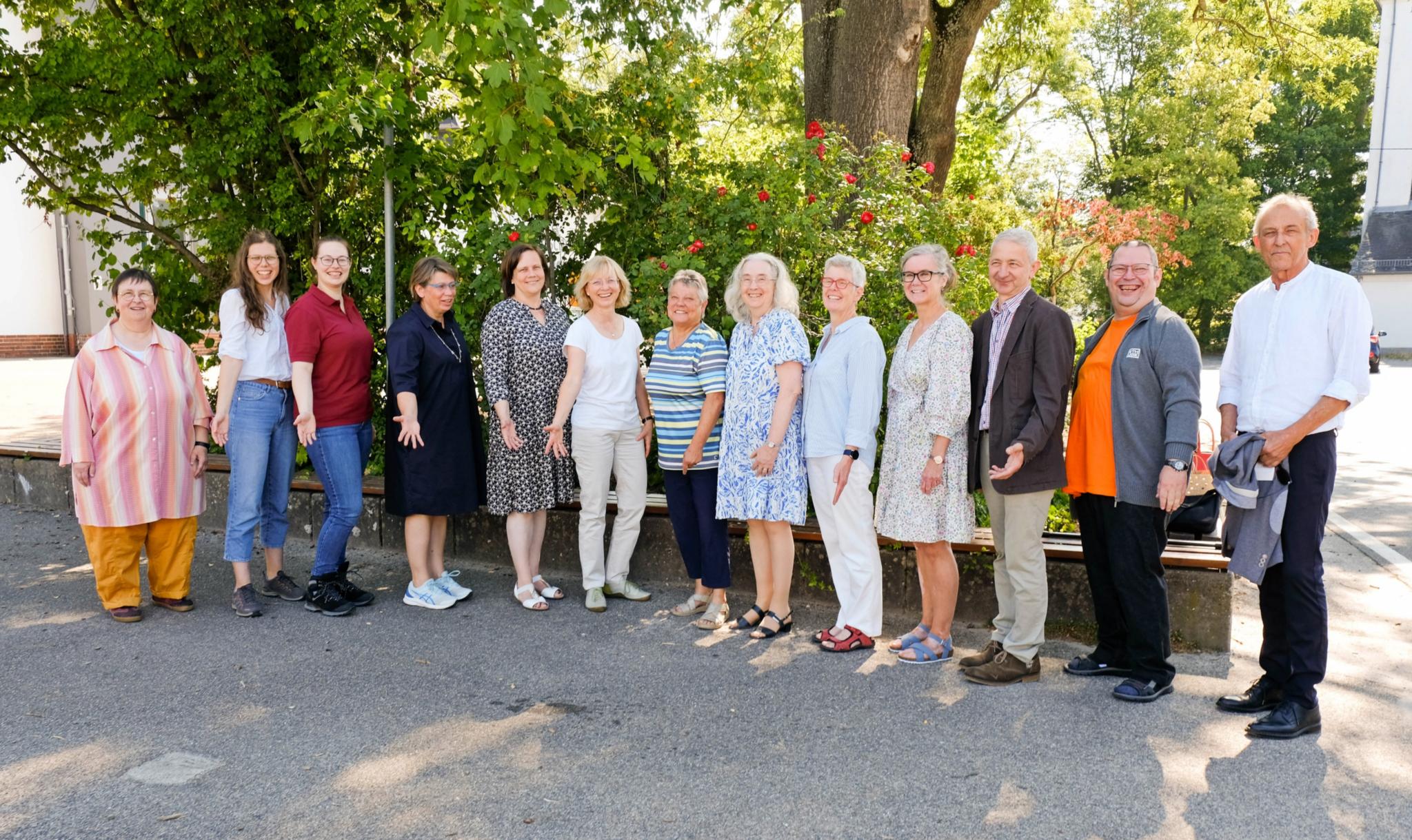 Gruppenfoto des Kirchenchors St. Beatus draußen im Hintergrund Büsche