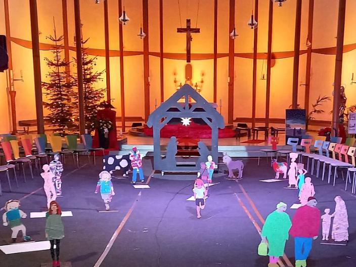 Vor dem in sanftem Licht beleuchteten Altarraum der St. Elisabethkirche steht eine außergewöhnliche Krippe. Wie ein Schwippbogen lebensgroß ist der Stall gestaltet mit Maria und Josef zwischen ihnen ein Stern. Holzfiguren aus Brettern gesägt - als Menschen, die uns tagtäglich auf der Straße begegnen, aber auch Ochs, Esel und Schaf kommen von der Krippe auf uns zu. Es entsteht das Gefühl auf einem Marktplatz oder auf einem Feld zu sein, denn dieses Krippe nimmt einen großen Raum ein.