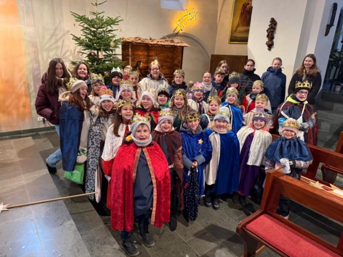 Eine fröhliche Sternsingergruppe mit ihren Betreuern, vor der Krippe der St. Martinus Kirche in Lay