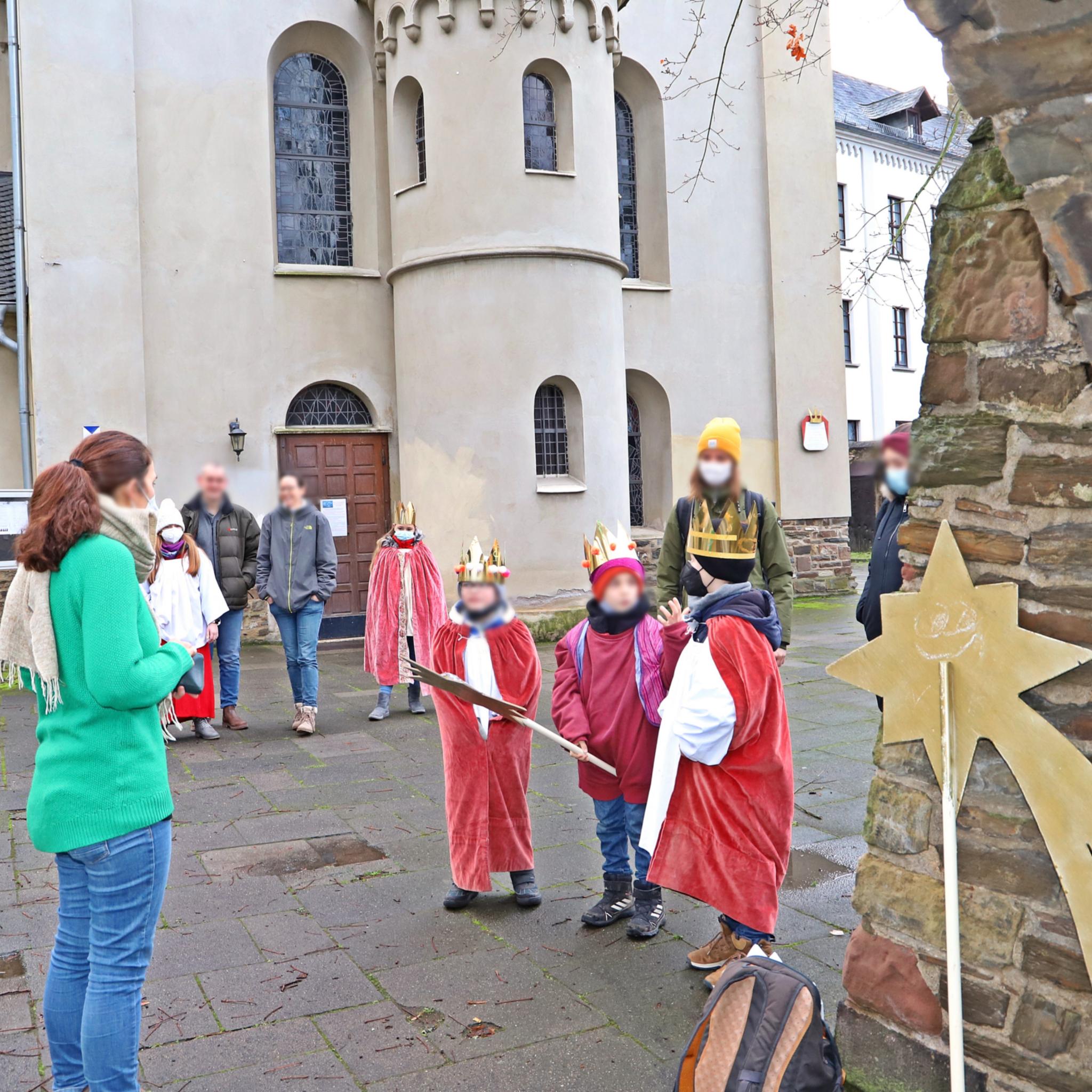 in Hintergrund die Kirche St. Laurentius, im Vordergrund die Organisatoren und einige Kinder im Sternsingergewand